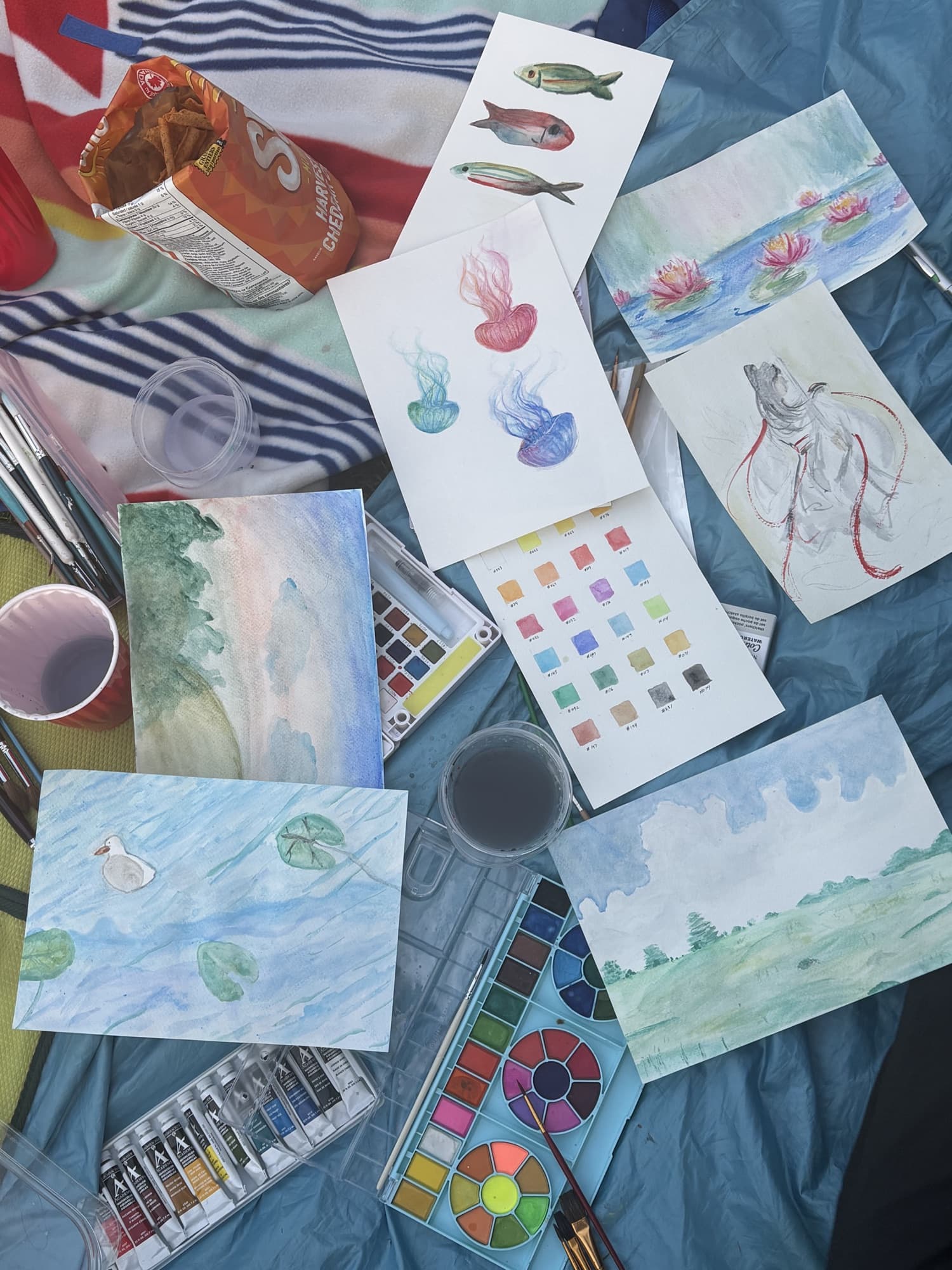 Watercolour paintings and paints spread across a table
